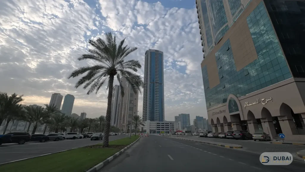Sharjah street with Al Salam Tower and palm trees